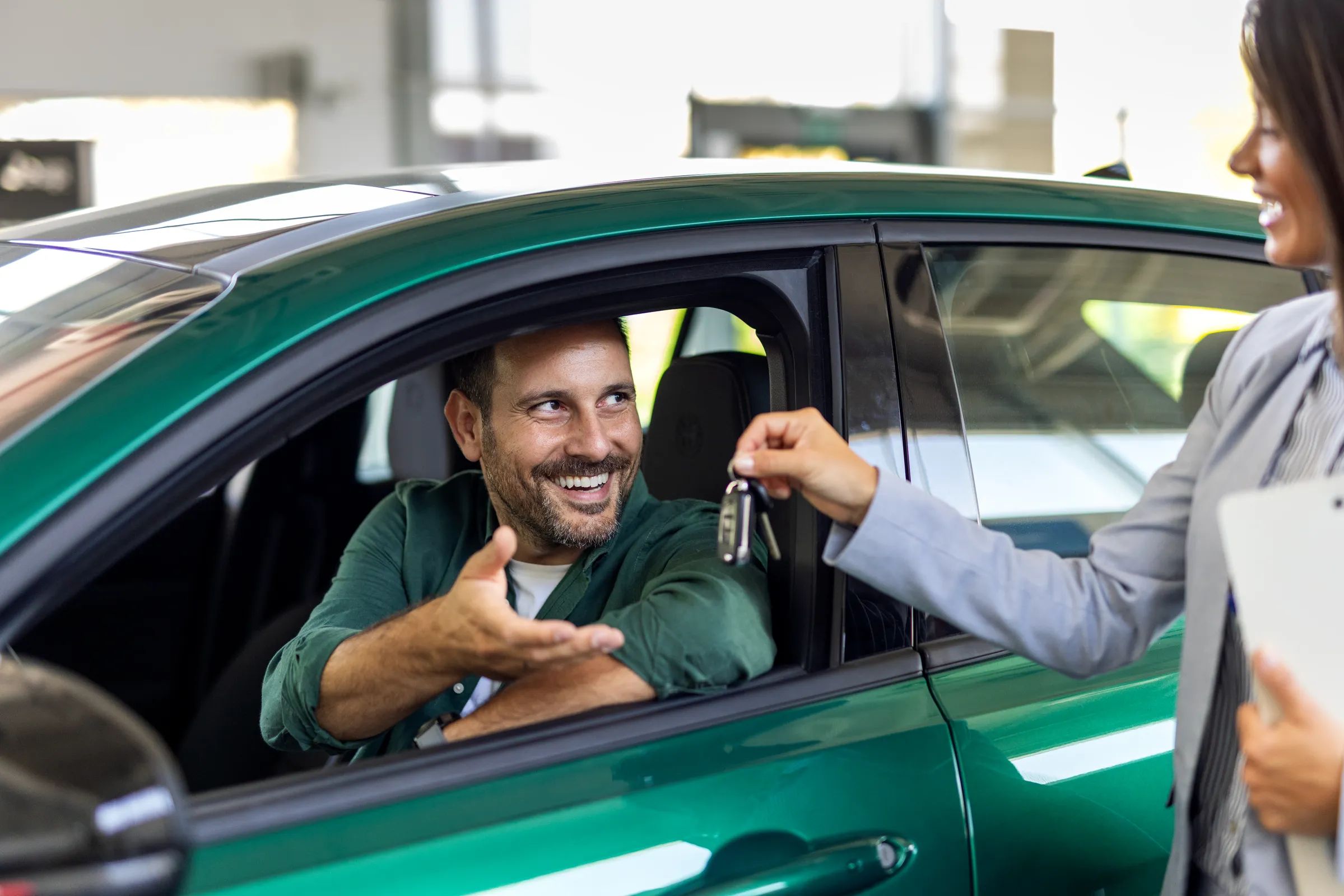 Un homme sourit en recevant les clés de sa nouvelle voiture, symbolisant l'achat ou le leasing.