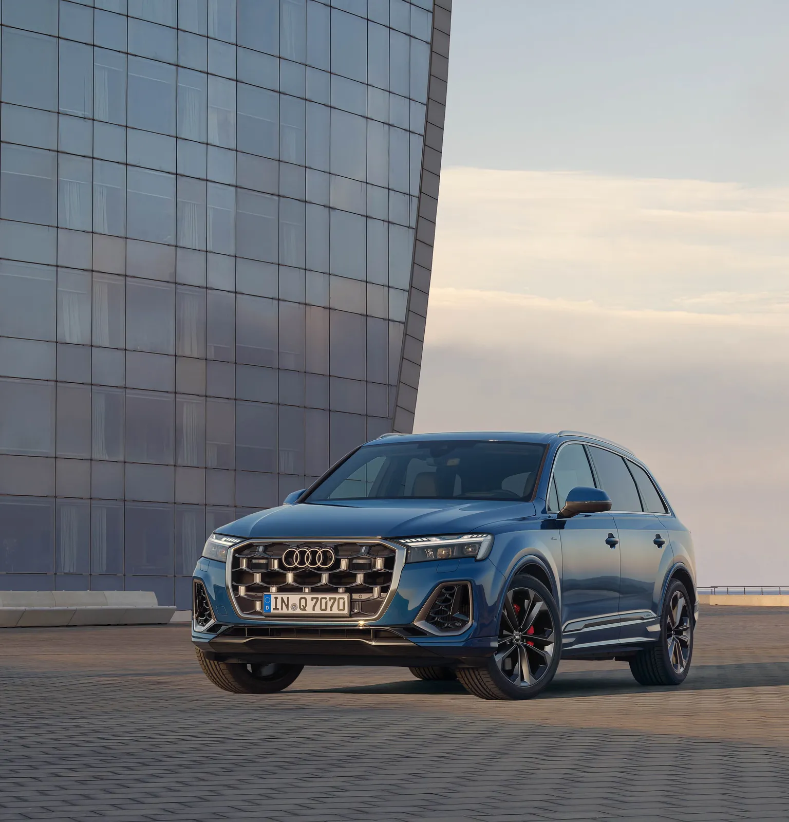Audi Q7 7 places bleu garé devant un bâtiment moderne