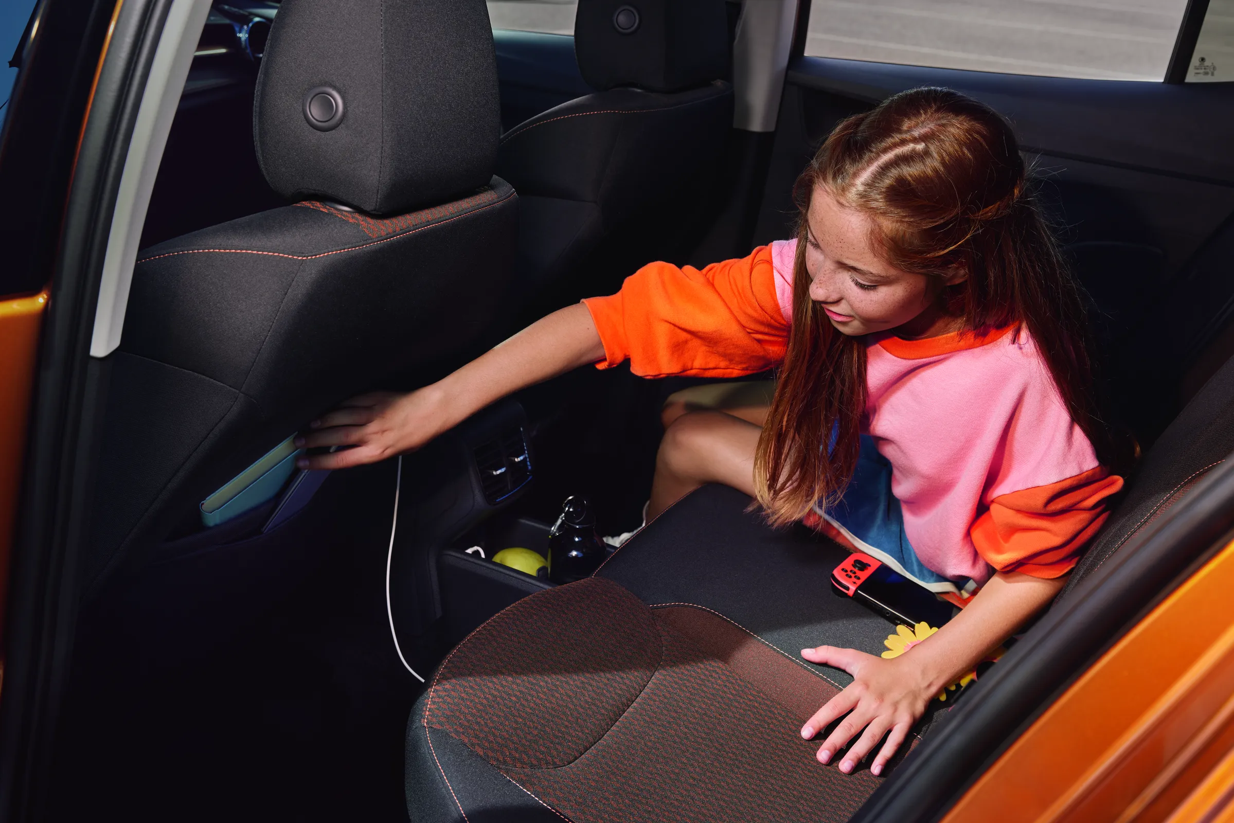 Enfant assise à l’arrière d’une Škoda Enyaq utilisant les rangements de porte