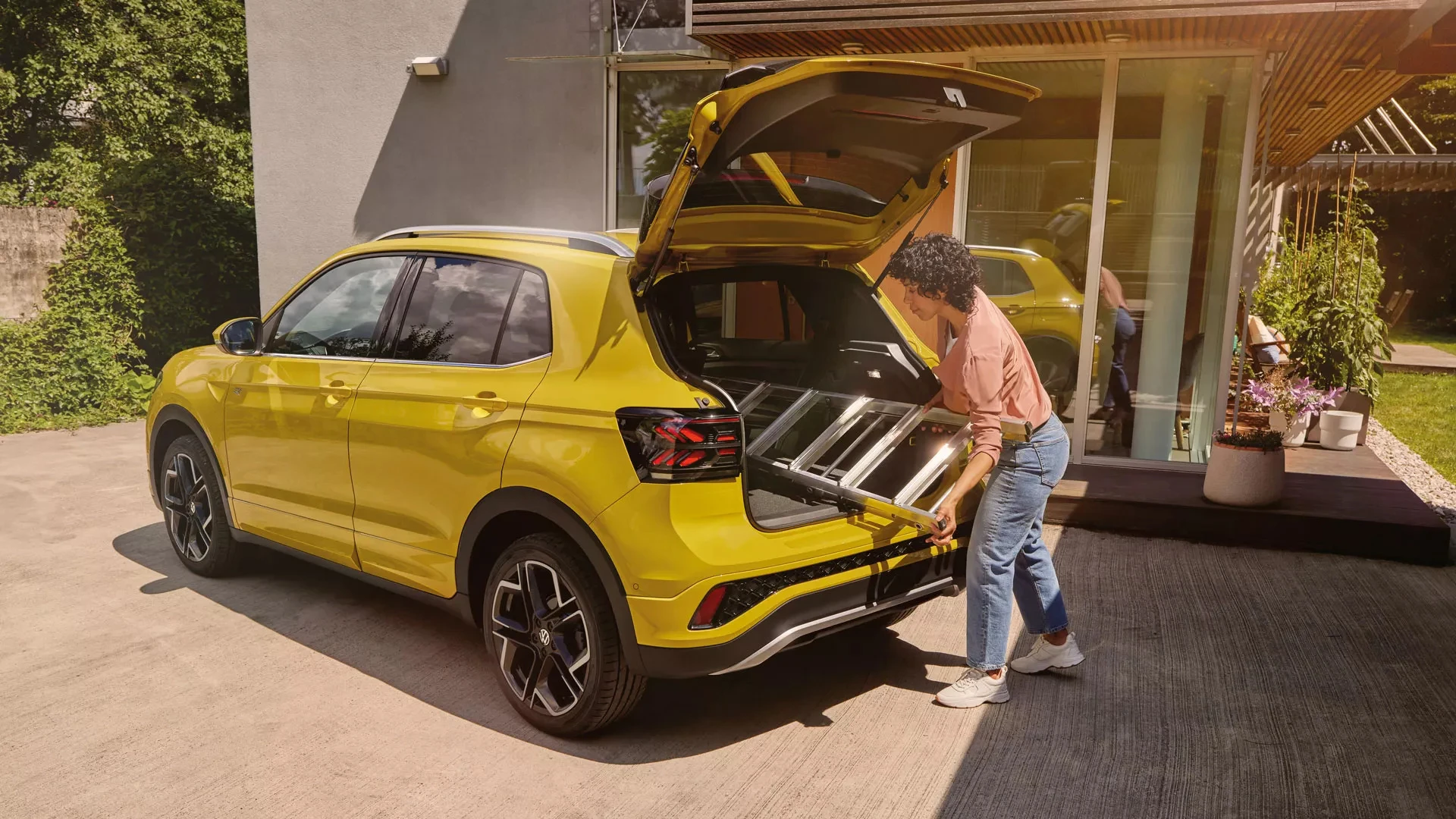 Volkswagen T-Cross jaune avec coffre ouvert, chargement d’une échelle dans le coffre