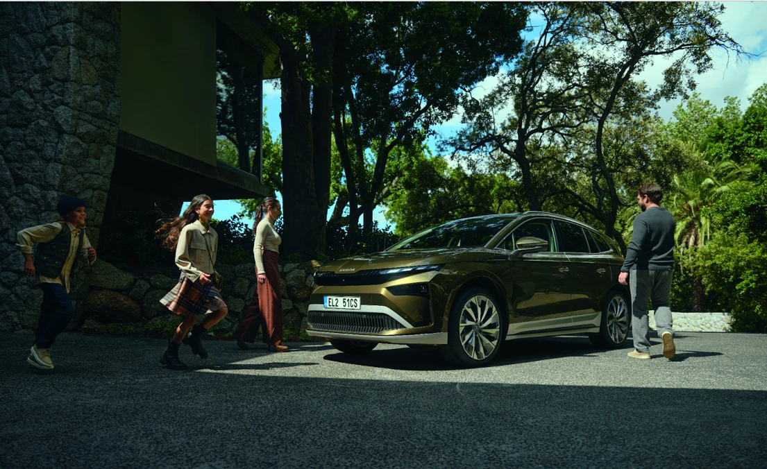 SUV électrique Škoda Enyaq garé devant une maison, avec une famille qui charge la voiture