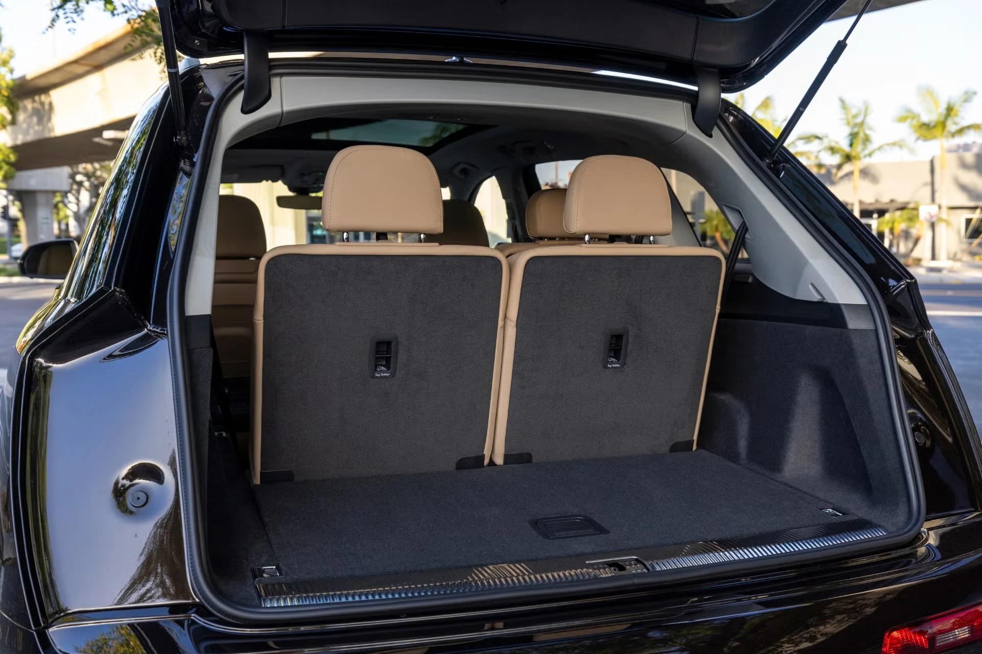Coffre d’un Audi Q7 noir avec le troisième rang de sièges relevé, montrant l’espace disponible en configuration 7 places