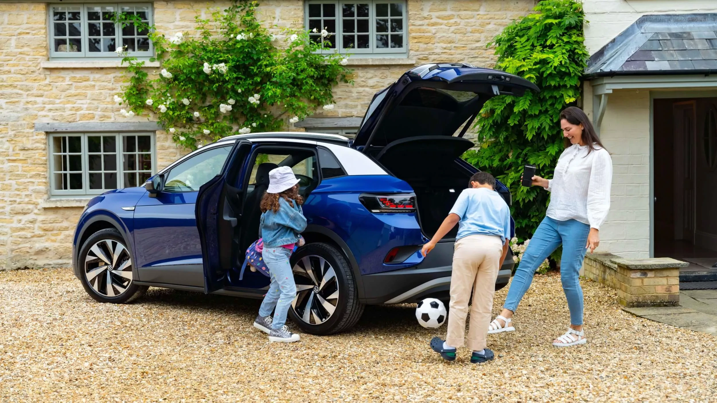 Volkswagen ID.4 électrique familiale avec coffre ouvert devant une maison