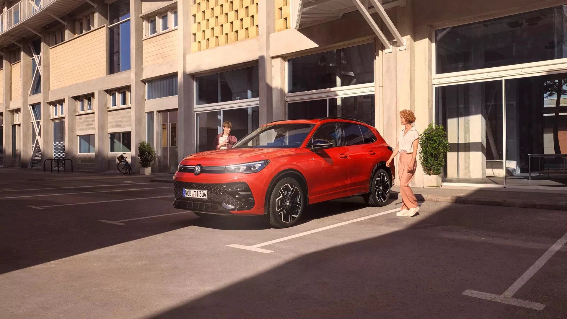 Volkswagen Tiguan rouge garé en ville devant un immeuble, SUV familial à faible consommation